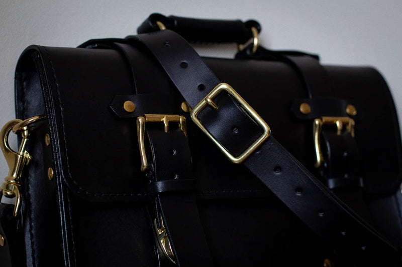 close up black leather satchel with brass