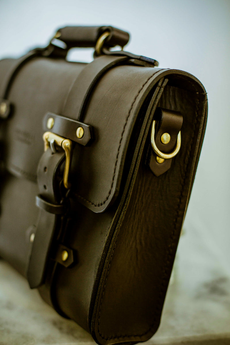 right side of oldenburg medium leather messenger bag in black with brass buckles  