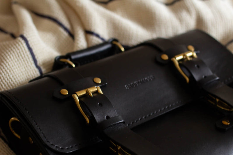 close up black leather satchel with solid brass