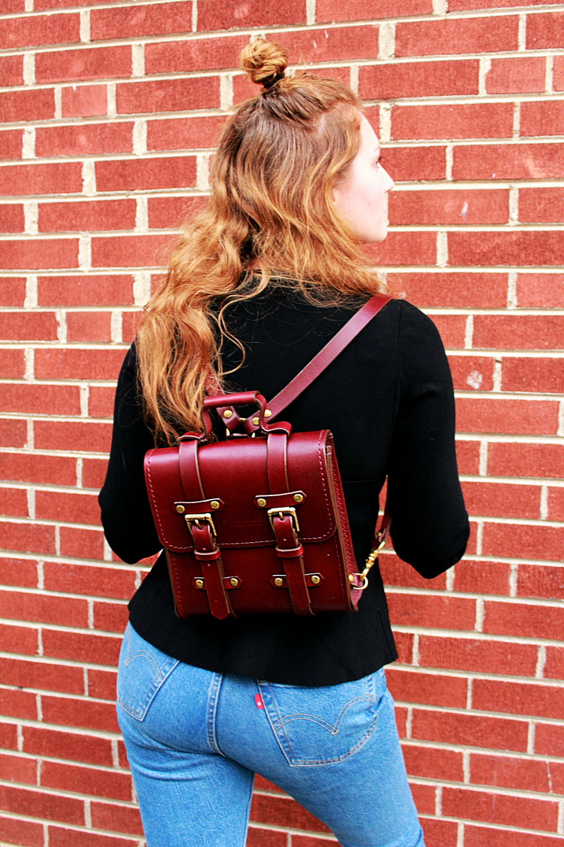 oxblood Sadelmager campus messenger with brass buckles worn as backpack