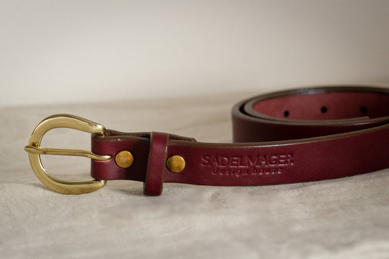 the noriker leather belt made in canada seen here on a white backdrop in red oxblood leather and solid brass hardware made in canada