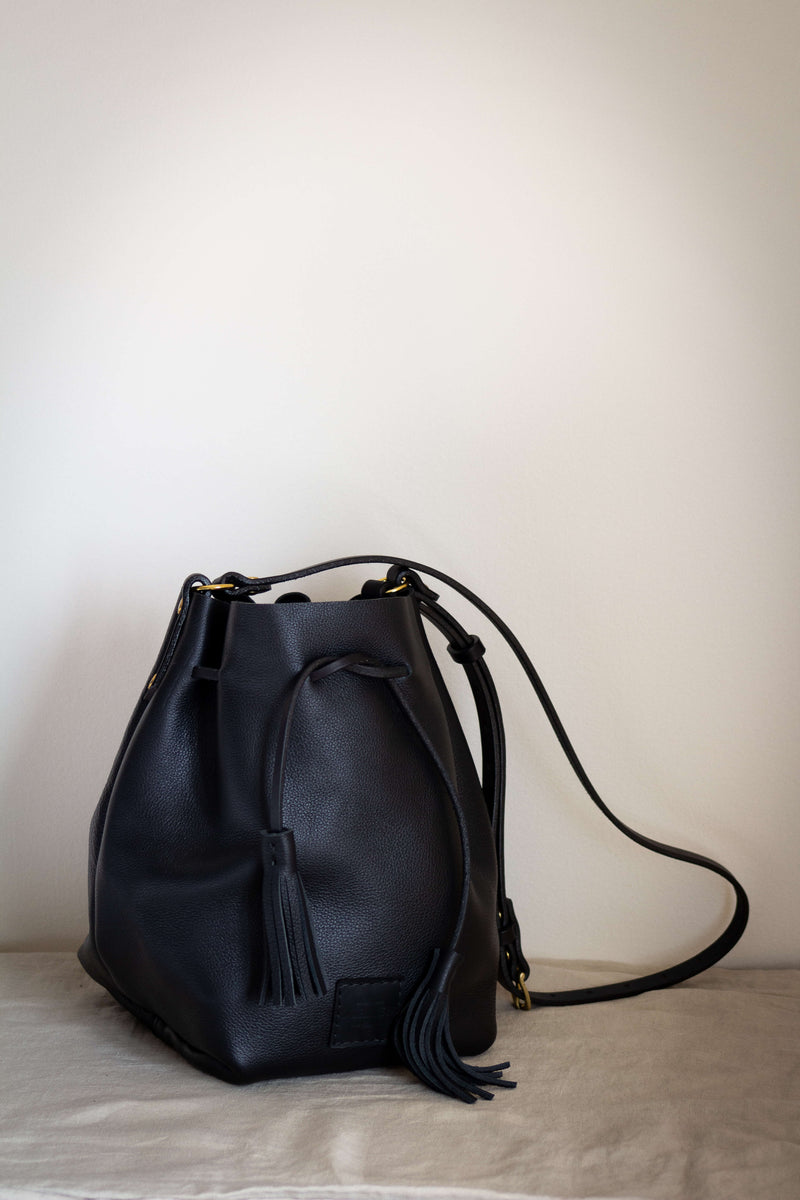 black leather suede bucket bag with solid brass and tassels worn crossbody fits lots of items and is made in Canada