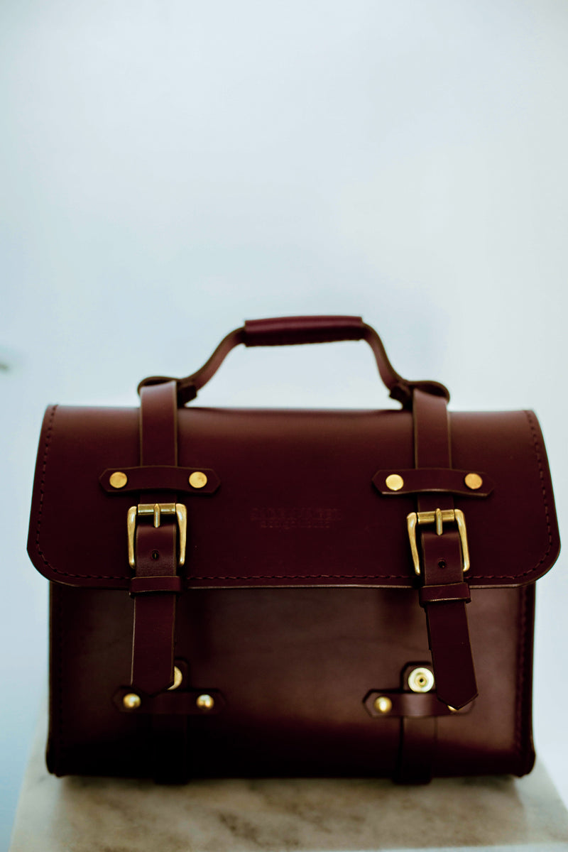 front side close up oldenburg small leather messenger bag in oxblood with brass buckles  