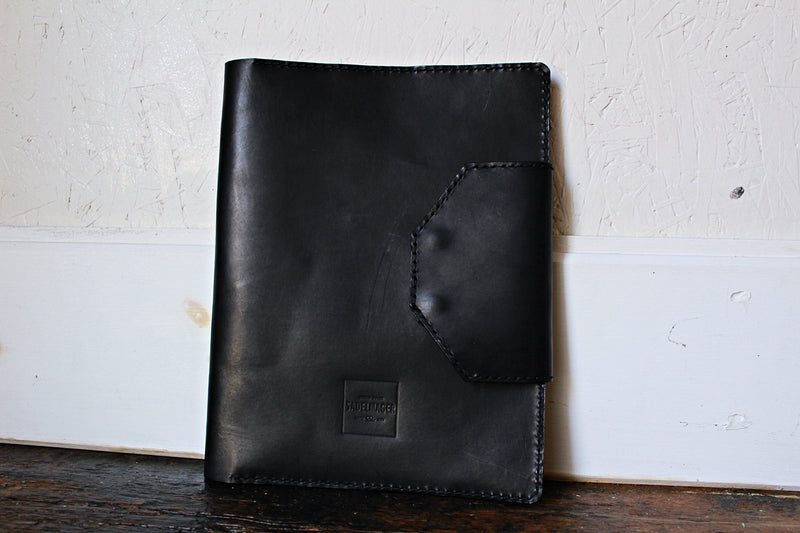 front side shire dossier notepad case in black against wall
